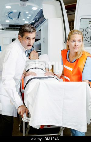 Paramedics pushing a patient on a gurney from an ambulance Stock Photo