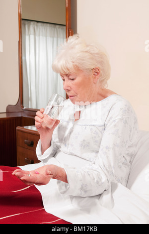 Woman sitting on the bed and taking medicine Stock Photo