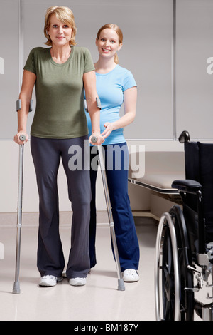 Physiotherapist assisting a patient in walking with crutches Stock Photo