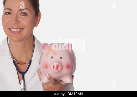 Female doctor holding a piggy bank Stock Photo