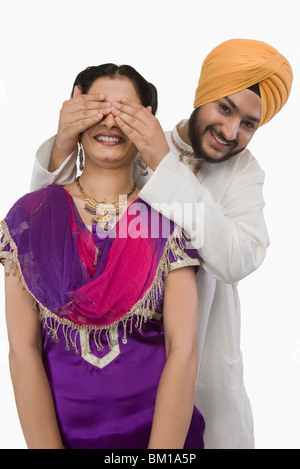 Sikh man covering a woman's eyes from behind Stock Photo