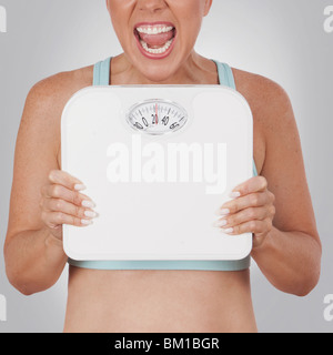 Close-up of a woman holding a bathroom scale and shouting in excitement Stock Photo