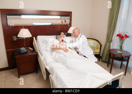 Doctor with a woman holding her newborn baby in a hospital Stock Photo