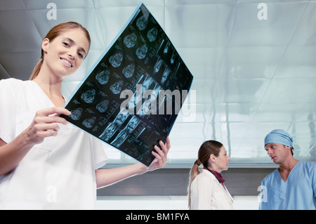 Female nurse examining an X-Ray with her colleagues discussing in the background Stock Photo