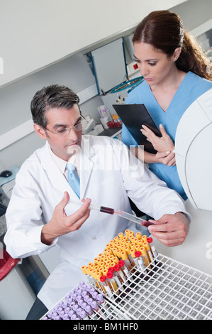 Lab technician filling blood in a test tube from a syringe Stock Photo