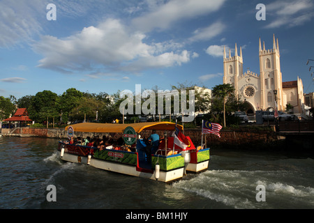 A tourist boat passes St Francis Xavier Church on the Malacca River in historical Malacca or Melaka, Malaysia. Stock Photo