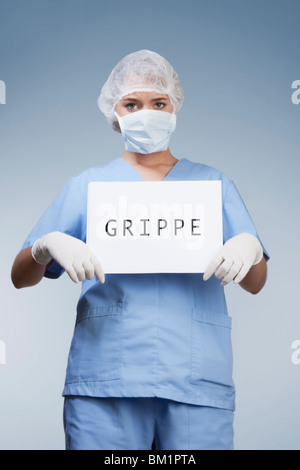 Portrait of a female surgeon showing a placard with word GRIPPE written on it Stock Photo