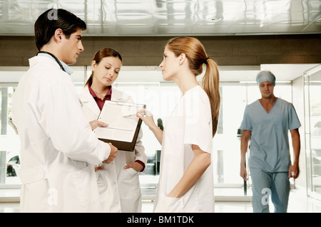 Three doctors discussing a clipboard Stock Photo