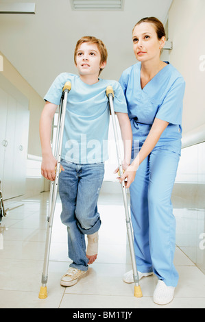 Female nurse assisting a boy on crutches Stock Photo