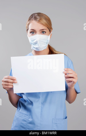 Female nurse wearing a flu mask and holding blank placard Stock Photo
