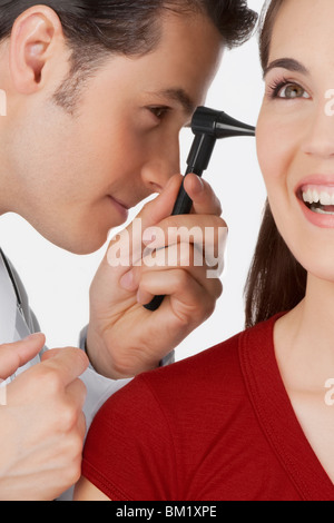Doctor examining a woman's ear with an otoscope Stock Photo