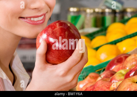 Woman holding an apple in a supermarket Stock Photo