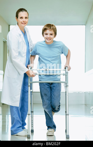 Female doctor assisting a boy with a walker Stock Photo