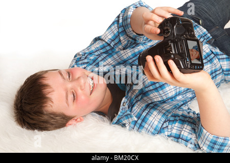 Boy with digital camera lying down and taking a self-portrait Stock Photo