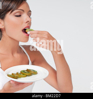 Woman eating sliced kiwi fruit Stock Photo