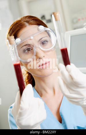 Female lab technician holding blood samples in test tubes Stock Photo