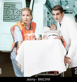 Paramedics pushing a patient on a gurney from an ambulance Stock Photo