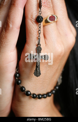 Woman praying with rosary Stock Photo
