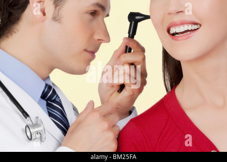 Doctor examining a woman's ear with an otoscope Stock Photo