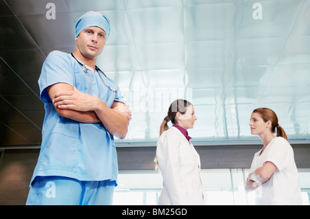 Male surgeon standing with his colleagues discussing in the background Stock Photo