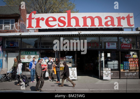 Strollers walk by Freshmart grocery store in Toronto Kensington Market Stock Photo