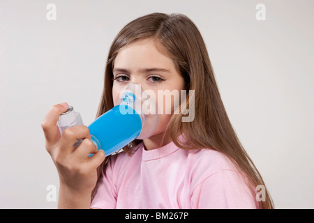 Girl using an asthma inhaler attached with a spacer Stock Photo