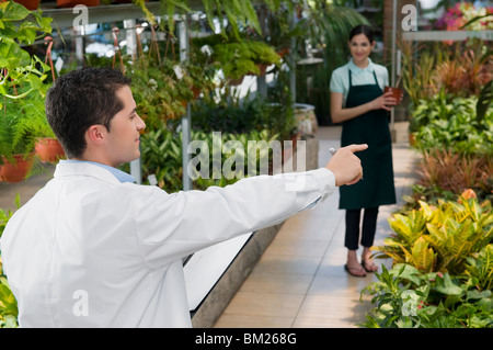 Scientist giving instructions to a woman in a greenhouse Stock Photo