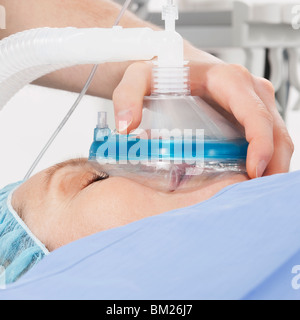 Anesthetist holding oxygen mask over patient's mouth in hospital Stock Photo