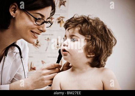 Female doctor examining a baby boy's ear with an otoscope Stock Photo
