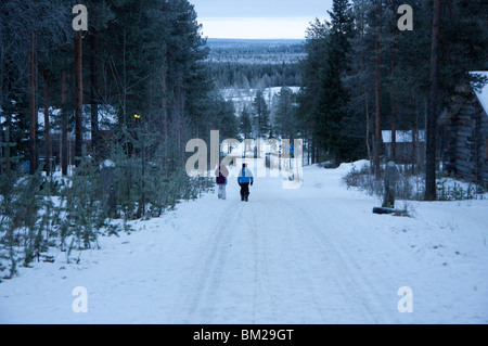 Two children walking along a snow covered road, Pyha-Luosto ski resort, Finnish Lapland, Finland, Scandinavia Stock Photo