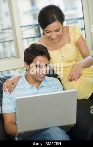 Couple sitting on a couch and working on a laptop Stock Photo