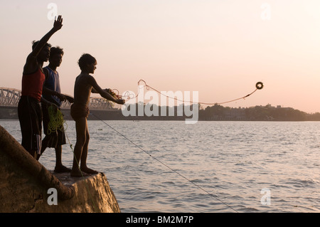 Young boys fishing for metal coins in the Howrah River, Kolkata (Calcutta), West Bengal, India Stock Photo