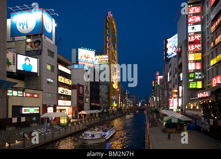 Tour boat on Dotonbori River glides past shops and restaurants in Namba, Osaka, Japan Stock Photo