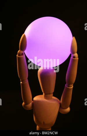 wooden mannequin holding a pink light ball over head Stock Photo