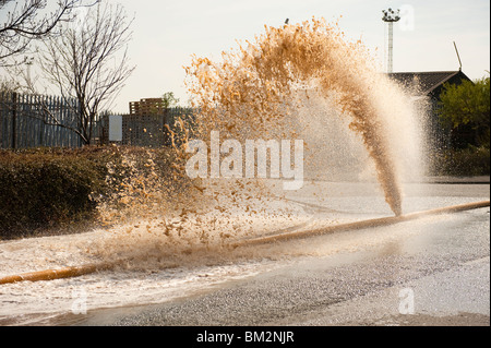 High Volume fire hose burst with water pouring out of leak Stock Photo