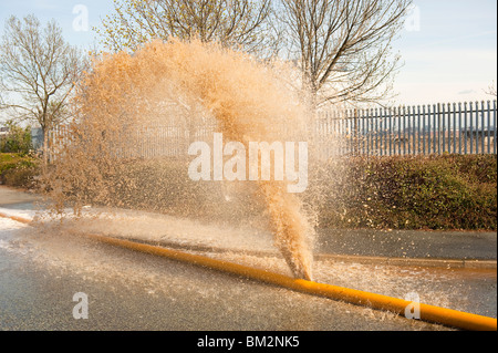 High Volume fire hose burst with water pouring out of leak Stock Photo