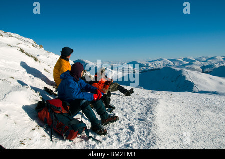 Walkers resting on the summit of Hopegill Head in winter, Grasmoor Fells, Lake District, Cumbria, England, UK Stock Photo