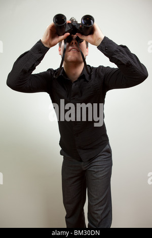 Young man wearing black shirt and holding binoculars, isolated on white Stock Photo