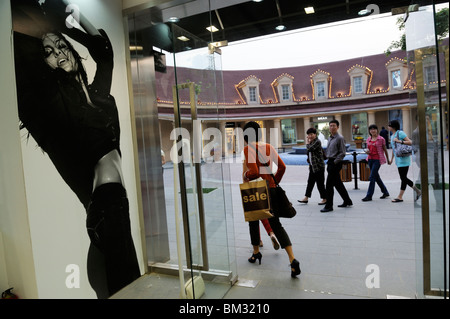 A Chinese lady leaves Calvin Klein Jeans store after shopping at Beijing Scitech Premium Outlet Mall in Beijing, China. 2010 Stock Photo