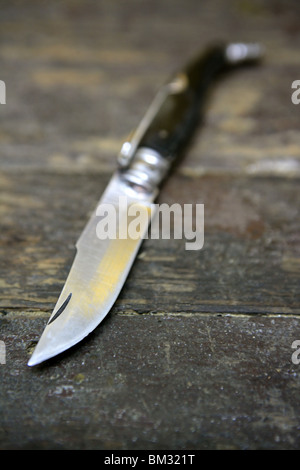 Open knife hand weapon over an aged wooden table Stock Photo