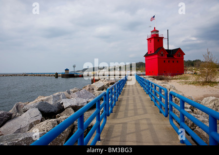 Tulip time festival Dutch Holland Michigan in USA Low angle distant view of Big Red Lighthouse with US flag and boardwalk with safety rails hi-res Stock Photo