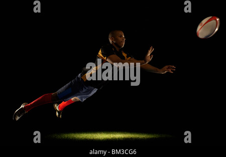 Rugby player diving whilst passing ball Stock Photo