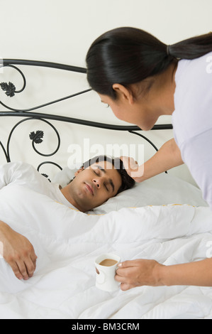 Woman making a man awake and holding tea cup Stock Photo