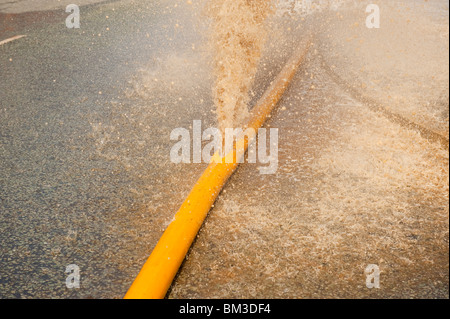 High Volume fire hose burst with water pouring out of leak Stock Photo