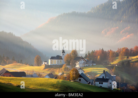 Sunbeams begin to break through the Autumn fog over Sorica in Zelezniki, Slovenia Stock Photo