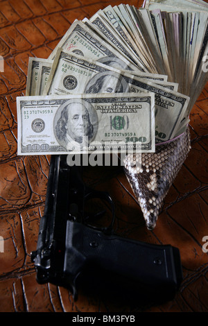 Dollar notes and gun, black pistol over crocodrile black fake leather Stock Photo