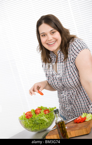 Cook - Plus size happy woman preparing vegetable salad with lettuce in modern kitchen Stock Photo
