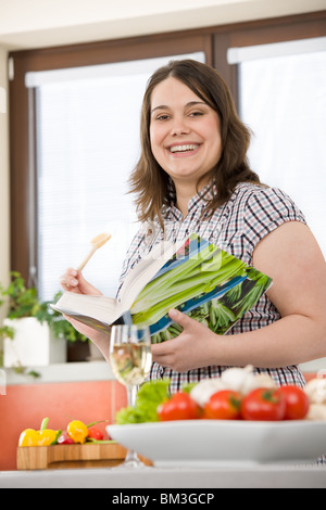 Cook - Plus size happy woman holding cookbook in kitchen Stock Photo