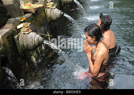 Pilgrims take a bath at the holy spring and temple of Tirta  Empul or Tirtha Empul in Bali, Indonesia. Stock Photo