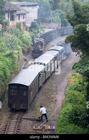 Two steam trains pass a manual switch at a station along the Jiayang steam rail-line in Leshan in Sichuan in China. Stock Photo